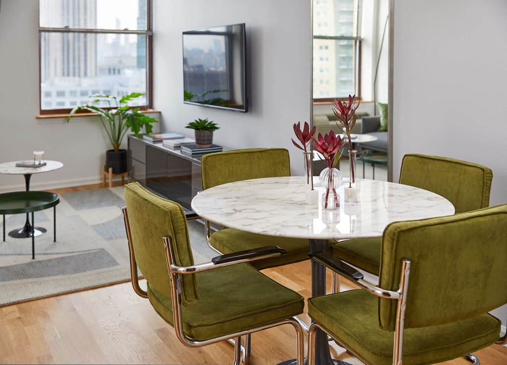 a dining room with a marble table and green chairs