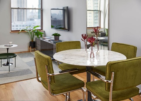 a dining room with a marble table and green chairs