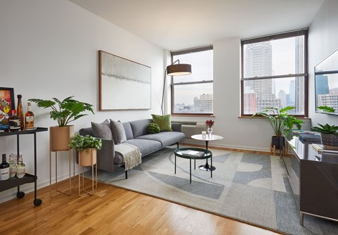 a living room with a couch and a table and three windows