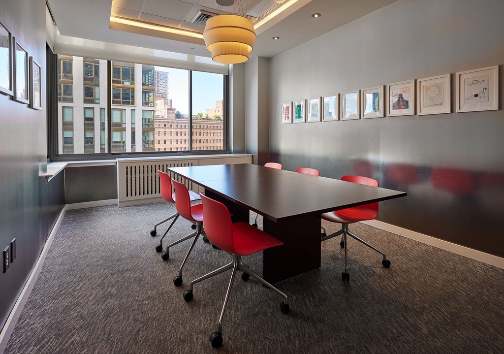 a conference room with a black table and red chairs