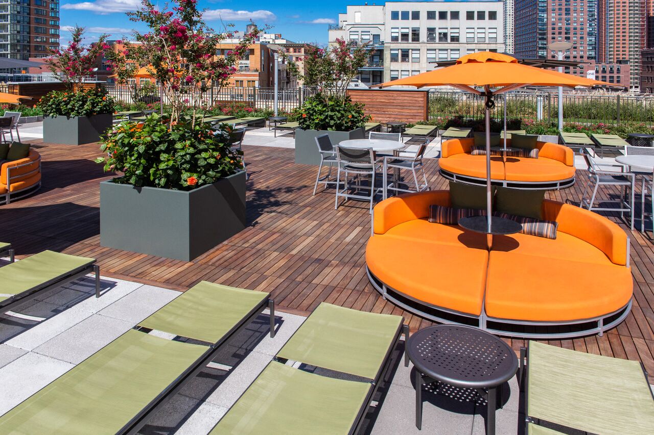 a roof top patio with tables and chairs and orange couches