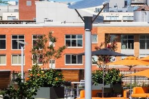 a lounge area on the rooftop of a building with orange couches and tables