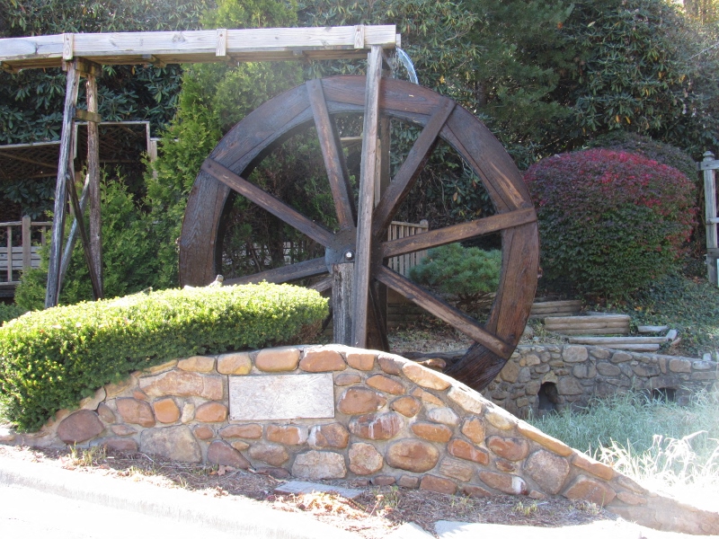 a large water wheel in front of a stone wall