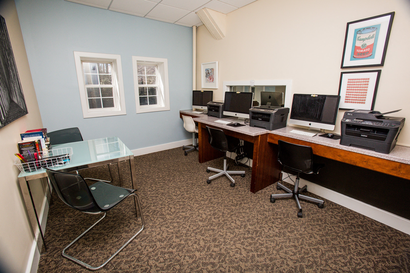 a computer room with three computer monitors and a glass table with chairs