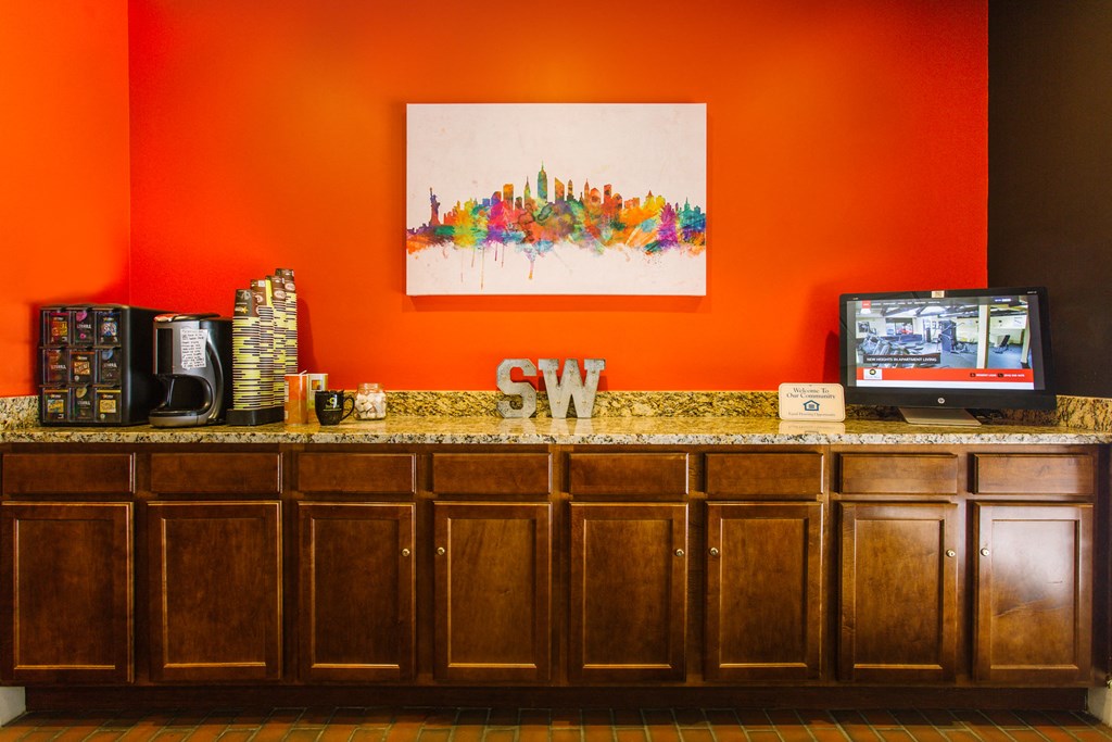 a counter in a hotel room with an orange wall and a television