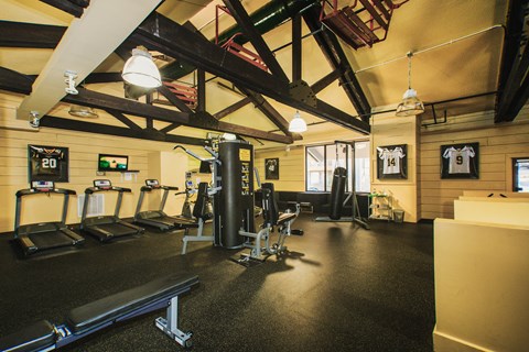 a gym with cardio equipment and weights on the floor