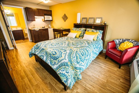 a bedroom with a bed and a kitchen