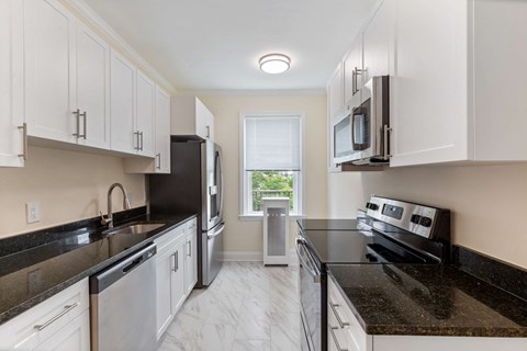 a kitchen with black counter tops and white cabinets