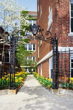 a sidewalk in front of a brick building with a wrought iron gate