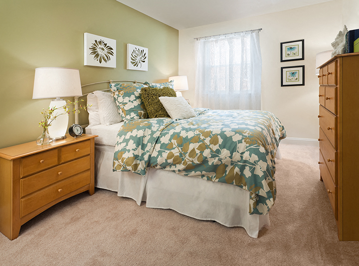 a bedroom with a bed and dressers and a window