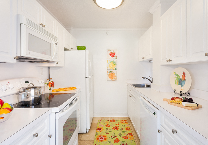 a kitchen with white cabinets and appliances and a white microwave
