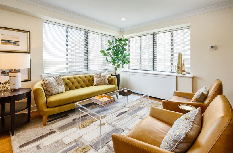 a living room with a yellow couch and a glass coffee table