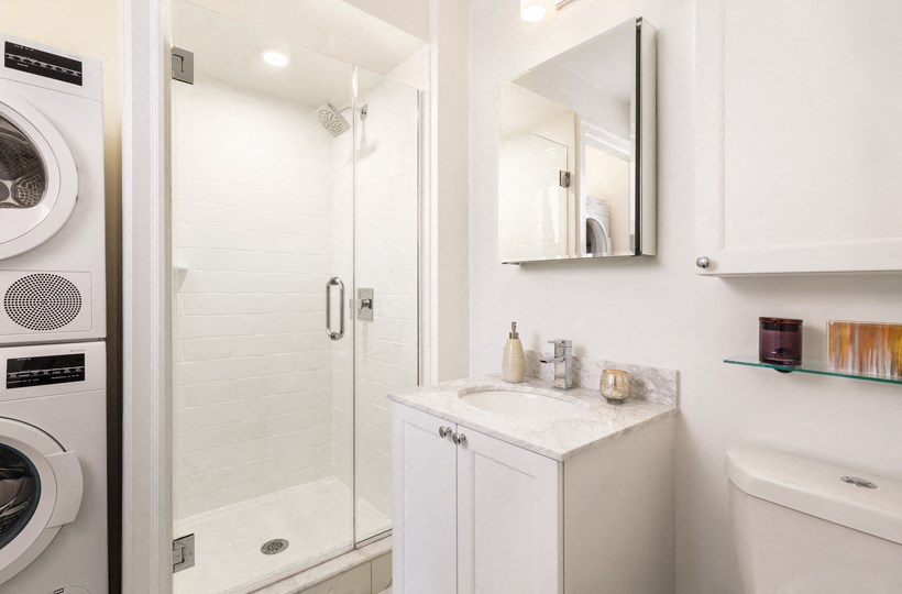 a white bathroom with a washer and dryer and a shower