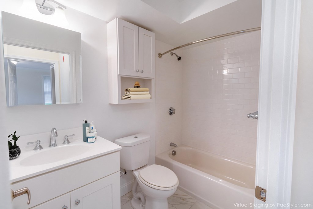 a white bathroom with a tub and a sink and a toilet