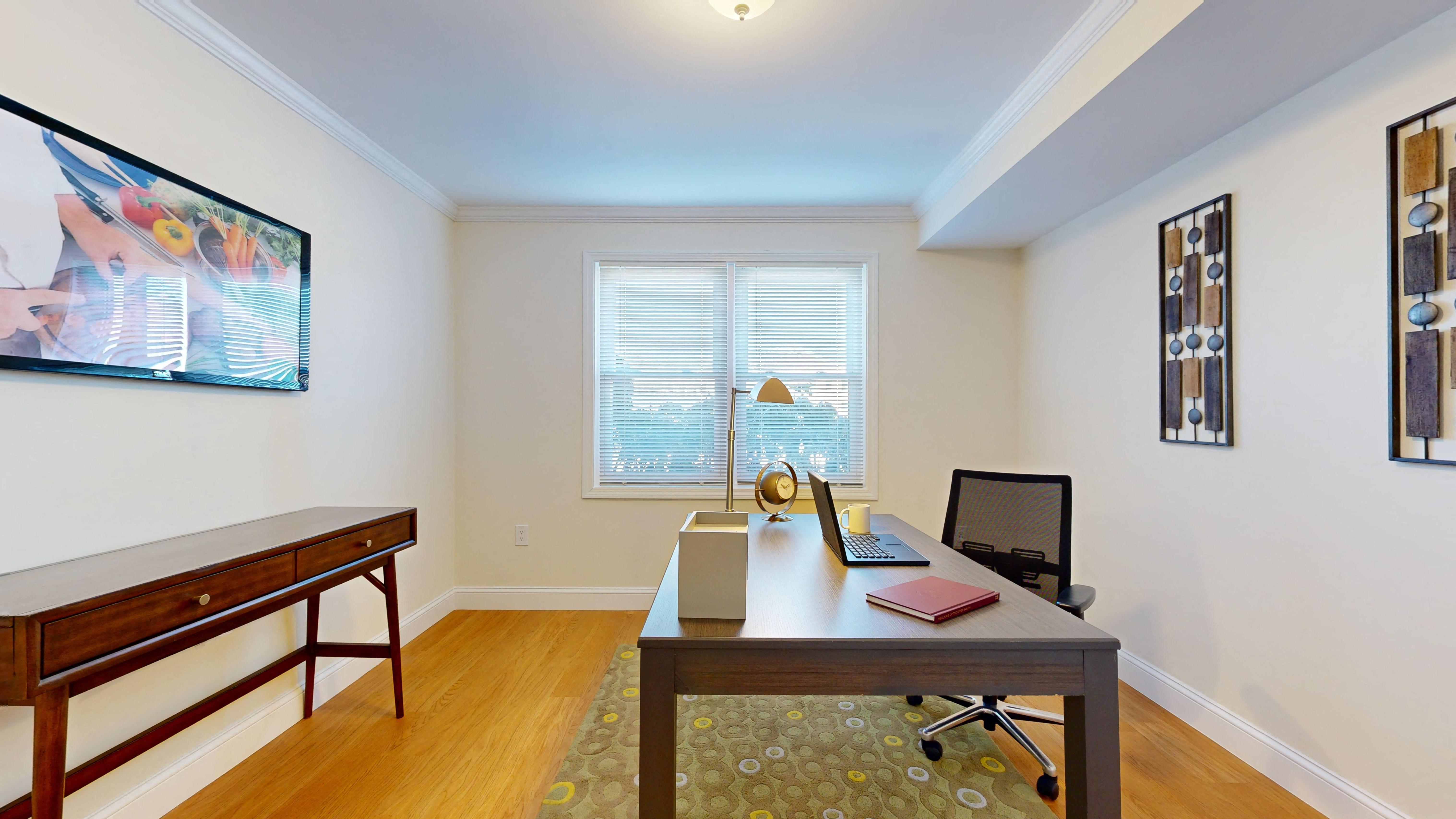 a home office with a desk and a large window