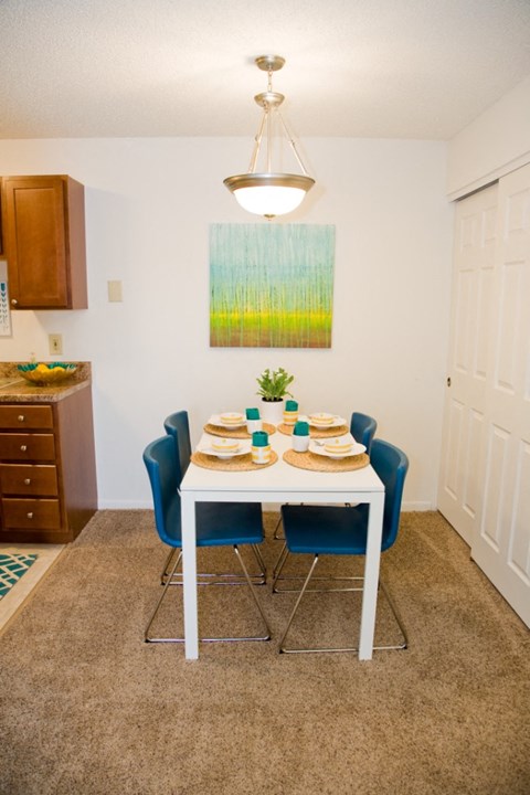 a dining room with a table and chairs and a painting on the wall