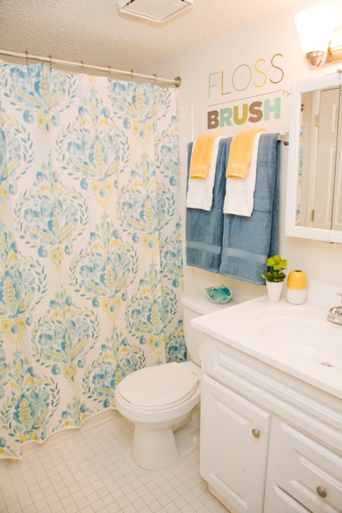 a white bathroom with a blue and white shower curtain