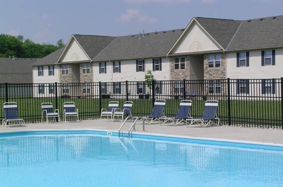 a swimming pool with chairs in front of a building