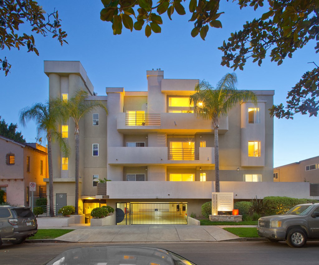 a street view of an apartment building with palm trees