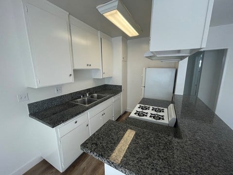 an empty kitchen with granite counter tops and white cabinets