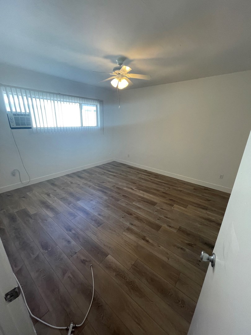 an empty room with wood flooring and a ceiling fan