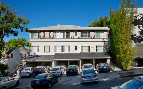 an apartment building with a parking lot full of cars