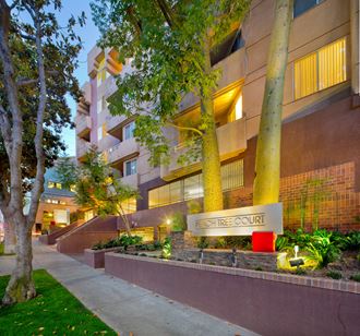 an apartment building with a sidewalk and trees in front of it