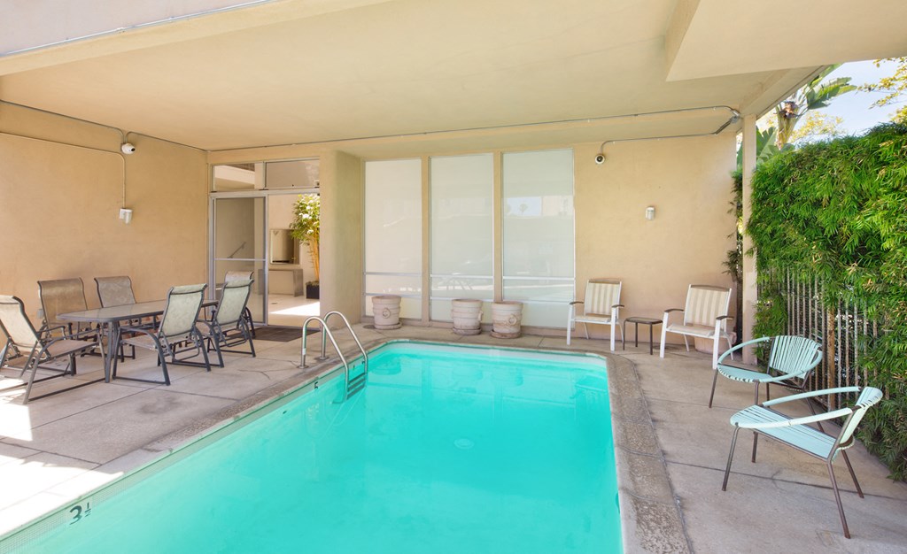 a swimming pool and patio with chairs and tables