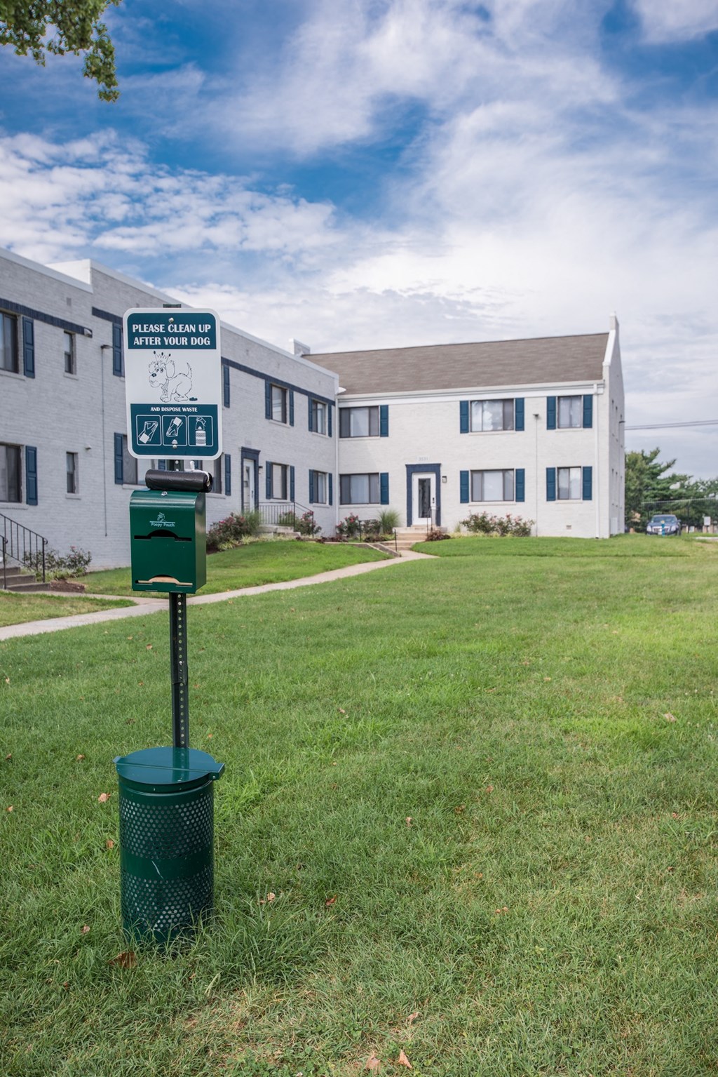 a street sign in the grass in front of an apartment building