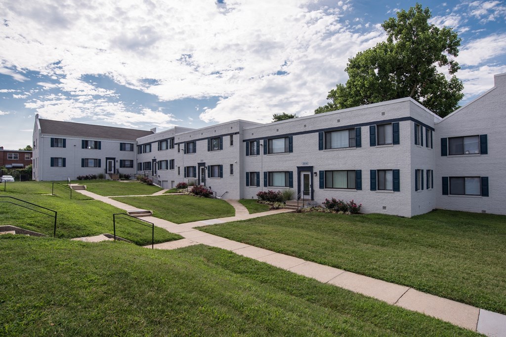 an apartment building with a green lawn and sidewalk