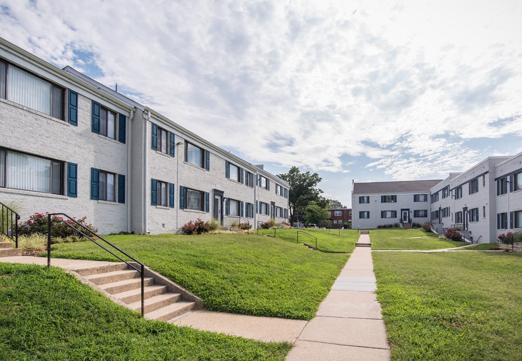 a row of apartment buildings with green grass and sidewalks
