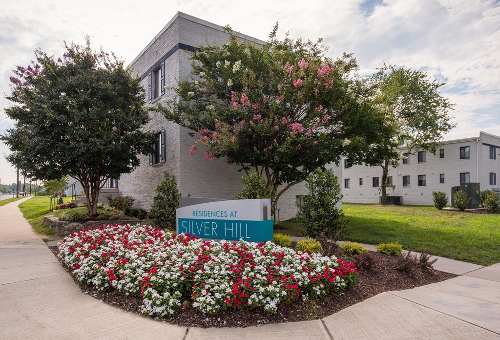 a building with a street sign and flowers in front of it