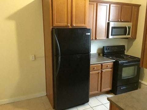 a kitchen with a black refrigerator and a stove