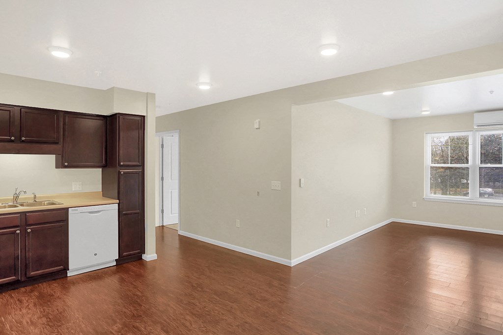 an empty kitchen and living room with wood flooring and a window