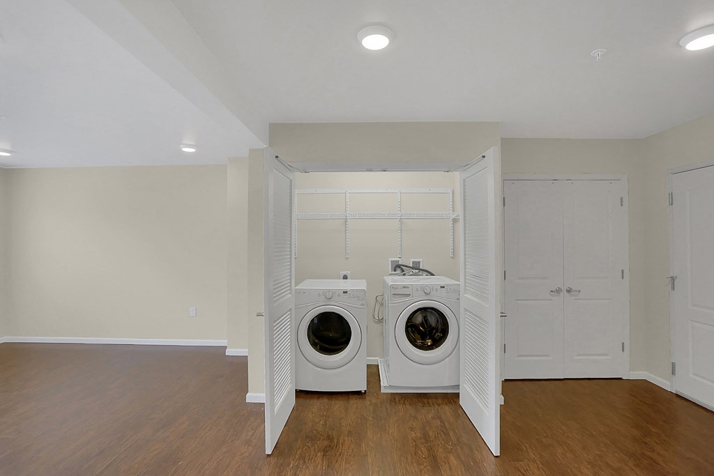 a washer and dryer in a laundry room with white walls and wood floors