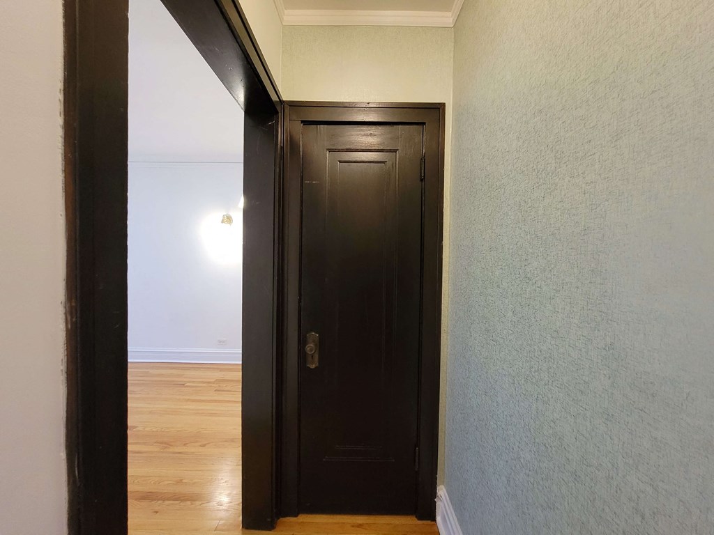 a door in a hallway with a wood floor and white walls