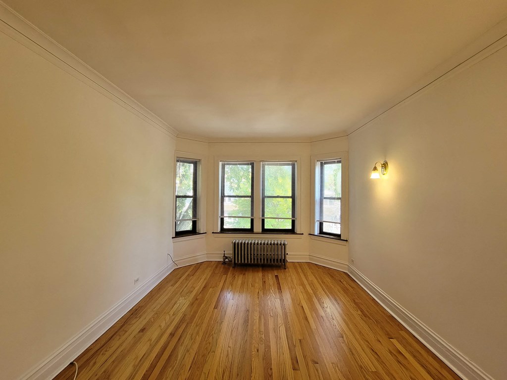 the living room of a home with a wood floor and windows