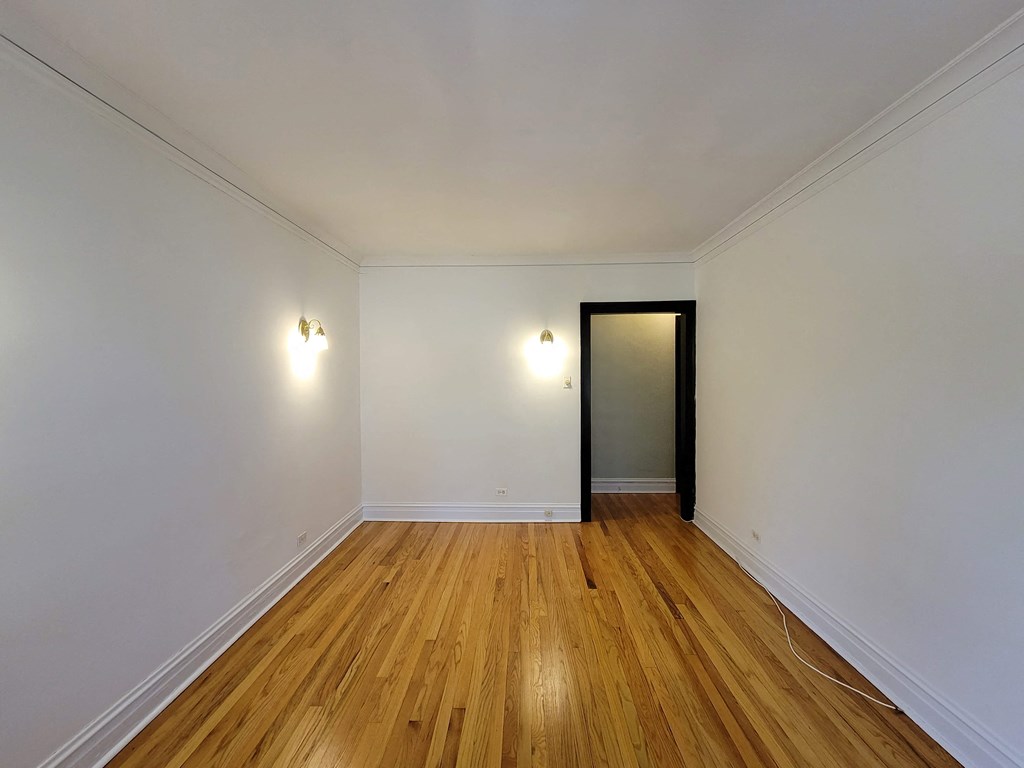 a living room with white walls and wooden floors and a black door