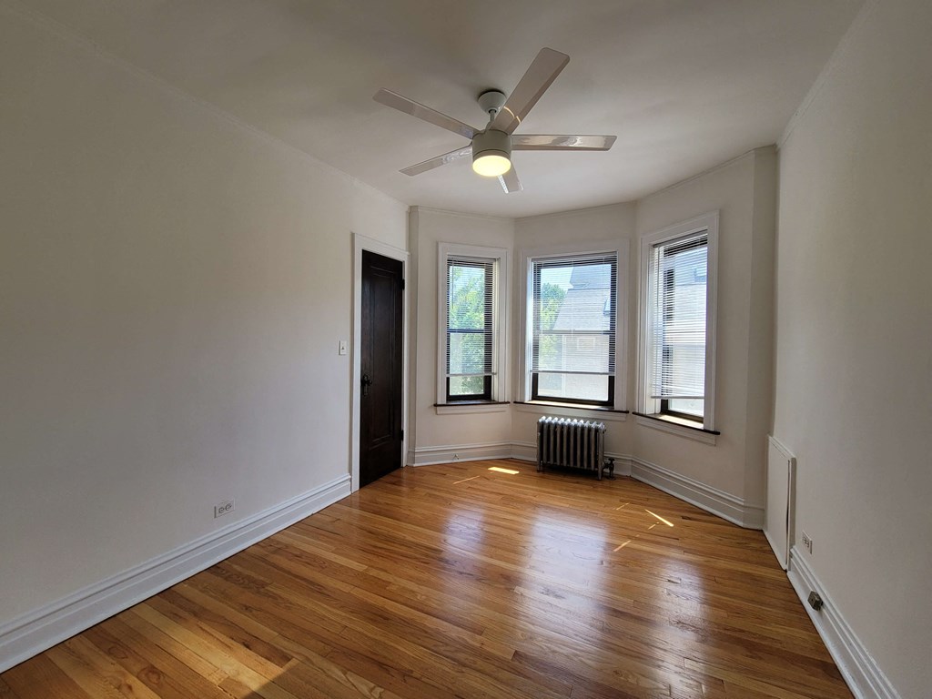 a living room with wood floors and a ceiling fan