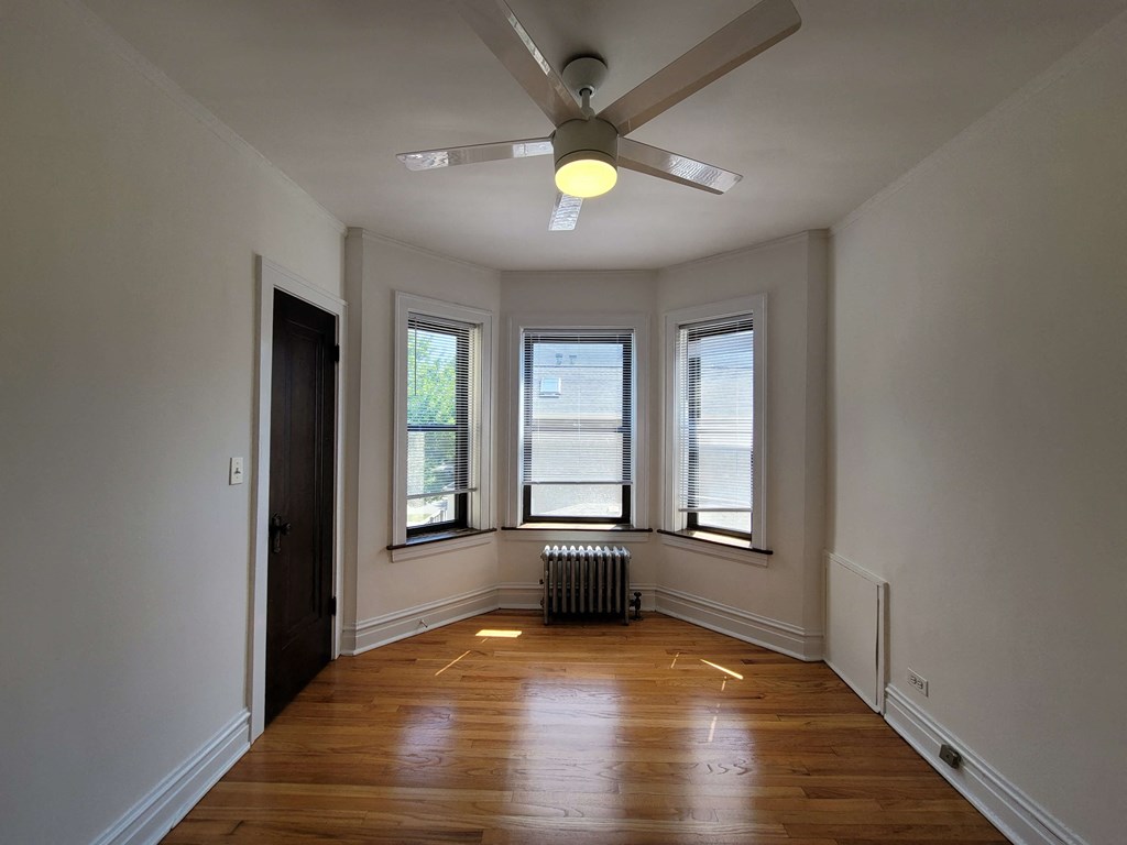 a living room with a ceiling fan and three windows