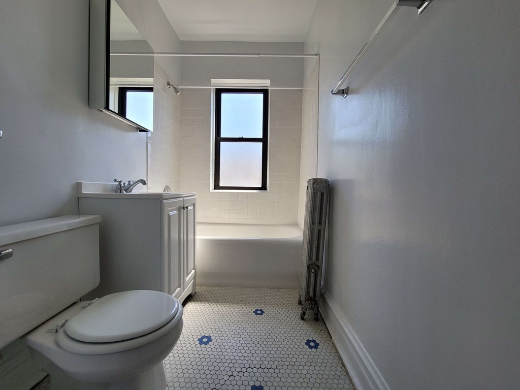 a white bathroom with a toilet and a window