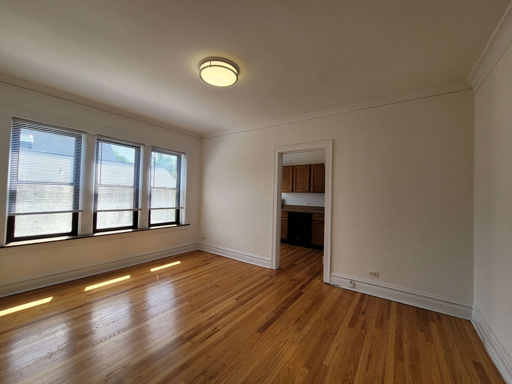 an empty living room with a hard wood floor and windows