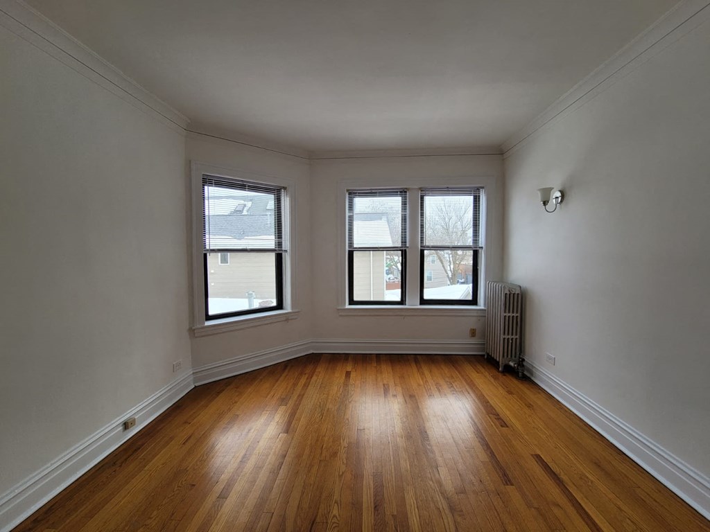 a living room with three windows and wooden floors