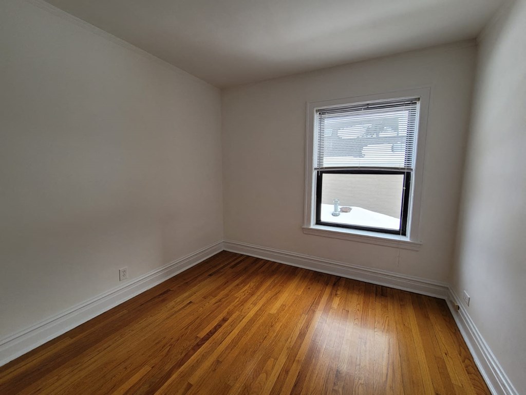 a small room with a window and wooden floors