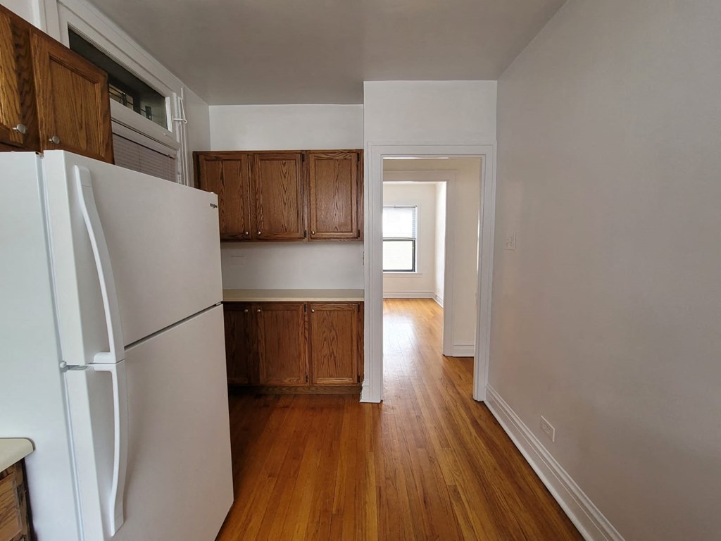 a kitchen with a refrigerator and wooden floors