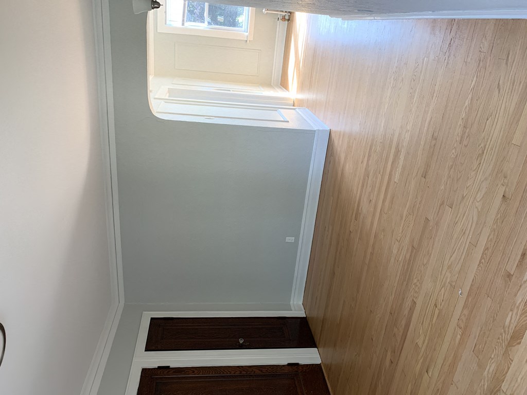 a small stairwell with a window and a wooden floor