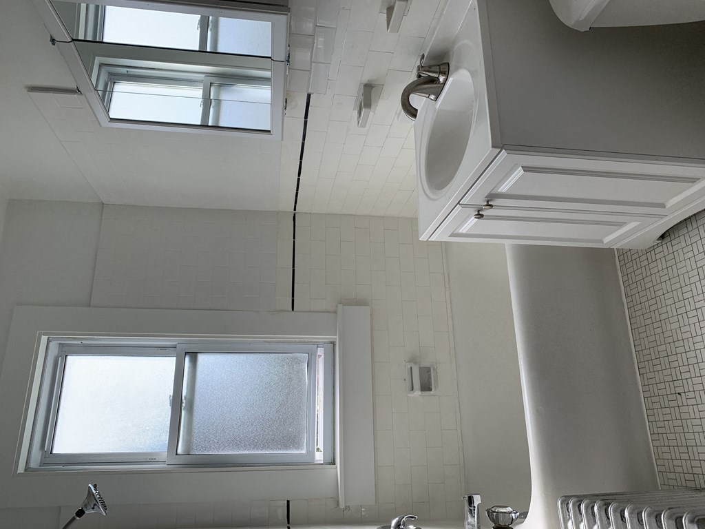 a bathroom with a window and a sink and a urinal