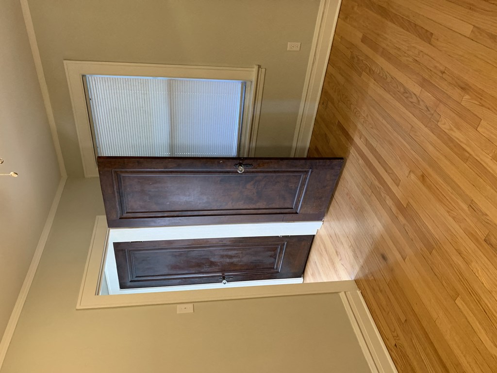the view from the top of the stairs looking down into the hall with wooden floors