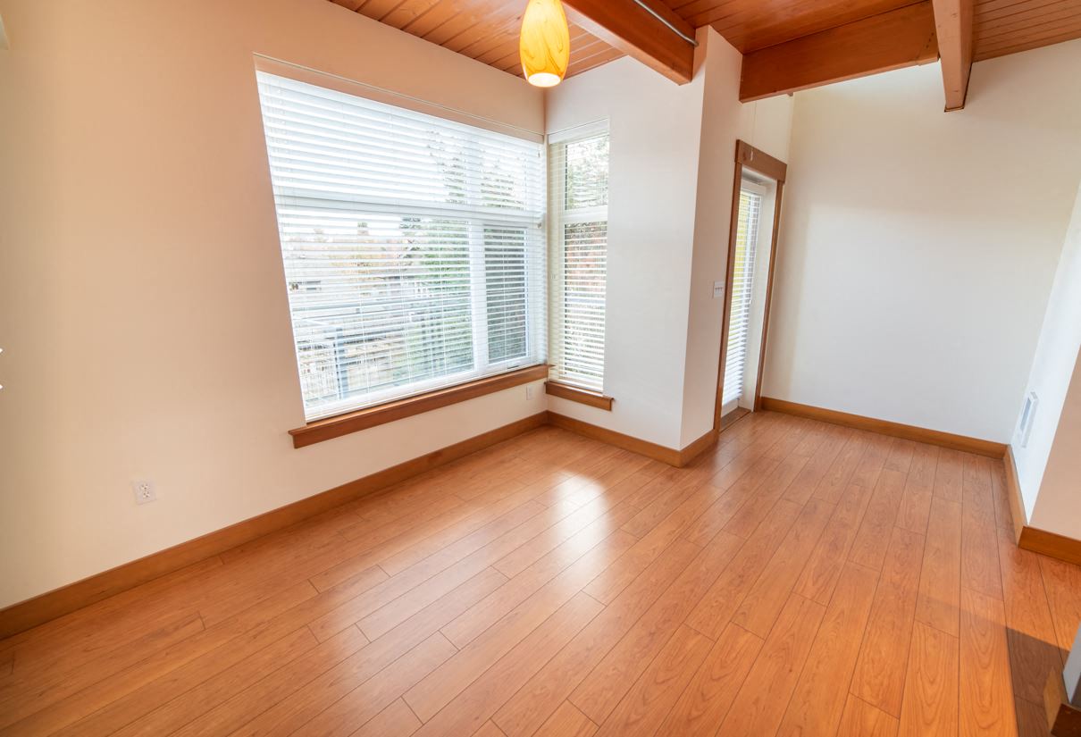 an empty living room with a large window and wooden floors