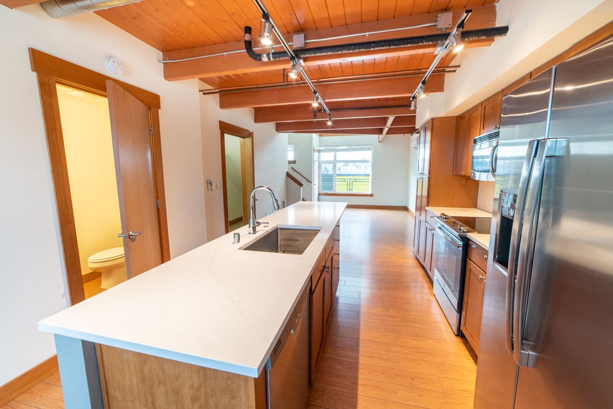 a large kitchen with a white counter top and stainless steel appliances